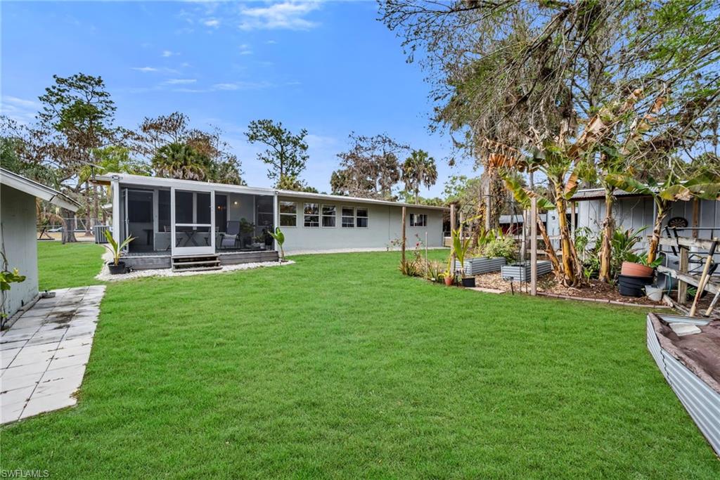 1840 23rd Street Southwest Naples, FL 34117 - Photo 47 of 50 Back of house featuring a lawn, a sunroom, and a patio