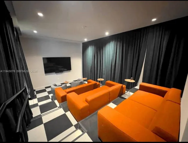 a blue bed sitting in a bedroom next to a flat screen tv with kitchen view