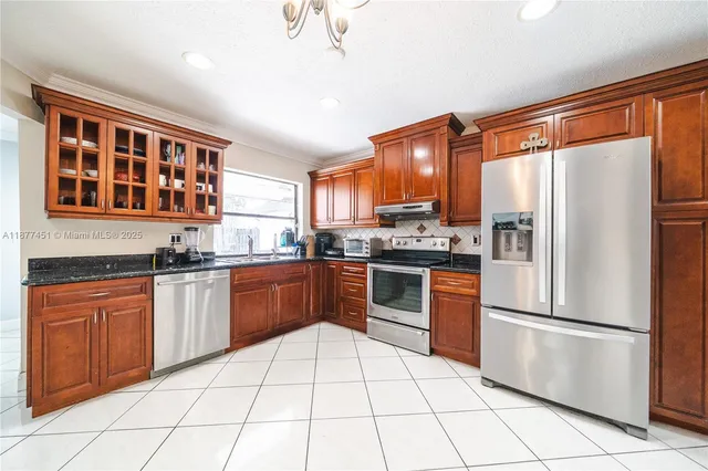 a kitchen with stainless steel appliances granite countertop a refrigerator stove top oven and sink