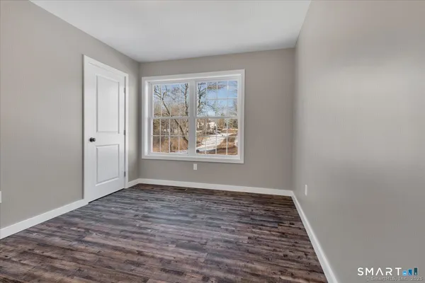 a view of an empty room with window and wooden floor