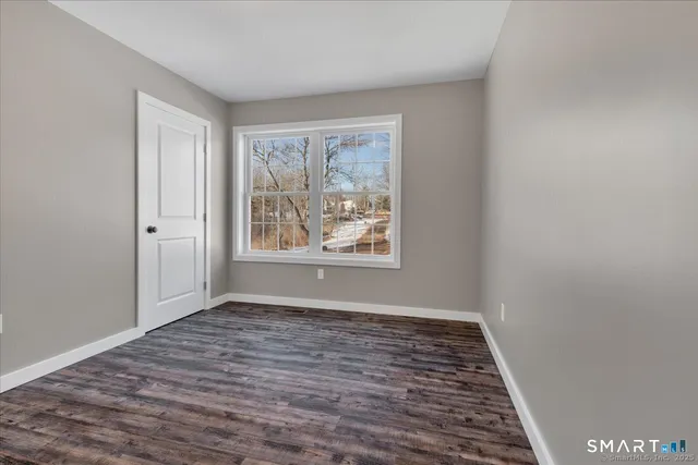 a view of an empty room with window and wooden floor
