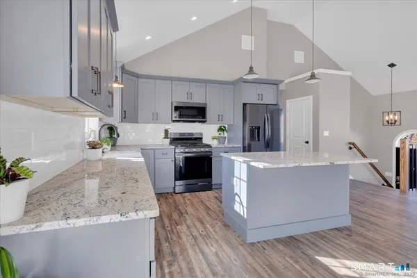 a large kitchen with stainless steel appliances granite countertop a stove a sink a refrigerator and a granite counter tops