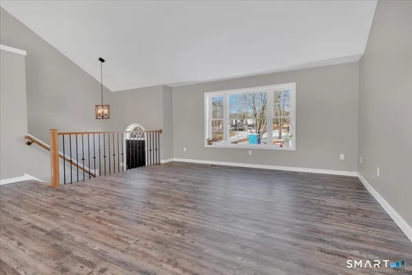 a view of an empty room with a window and wooden floor