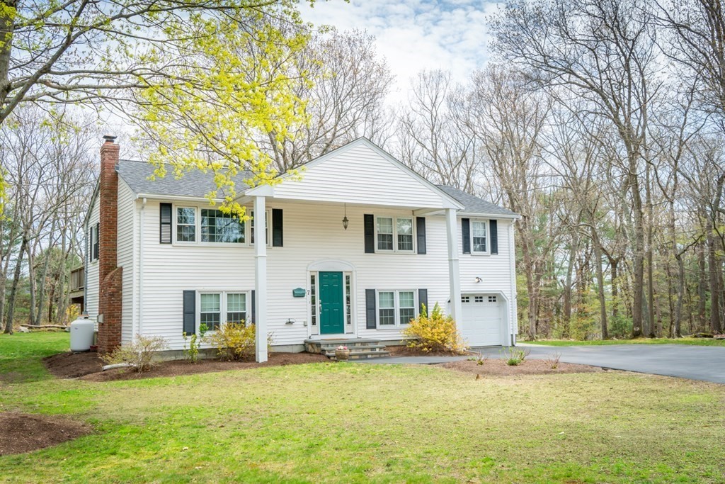 a front view of a house with a large tree and plants
