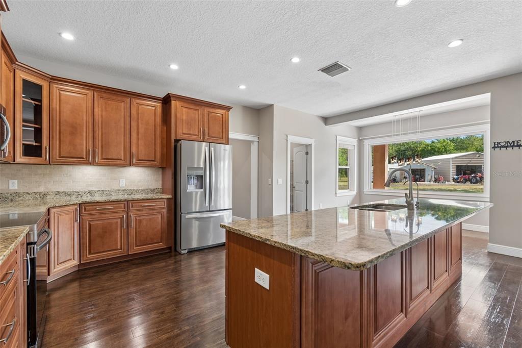 29913 Darby Road Dade City, FL 33525 - Photo 16 of 100 a kitchen with stainless steel appliances granite countertop a sink dishwasher stove and refrigerator with wooden floor