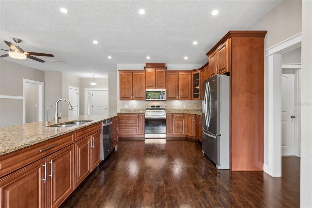 29913 Darby Road Dade City, FL 33525 - Photo 19 of 100 a kitchen with stainless steel appliances granite countertop a refrigerator a sink dishwasher a stove and a wooden floors