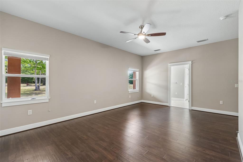 29913 Darby Road Dade City, FL 33525 - Photo 60 of 100 an empty room with wooden floor chandelier fan and windows