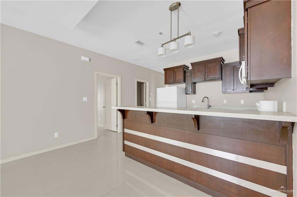 3004 South L Street, Unit 4 McAllen, TX 78503 - Photo 7 of 13 a spacious kitchen with stainless steel appliances a sink dishwasher a refrigerator and white cabinets with wooden floor
