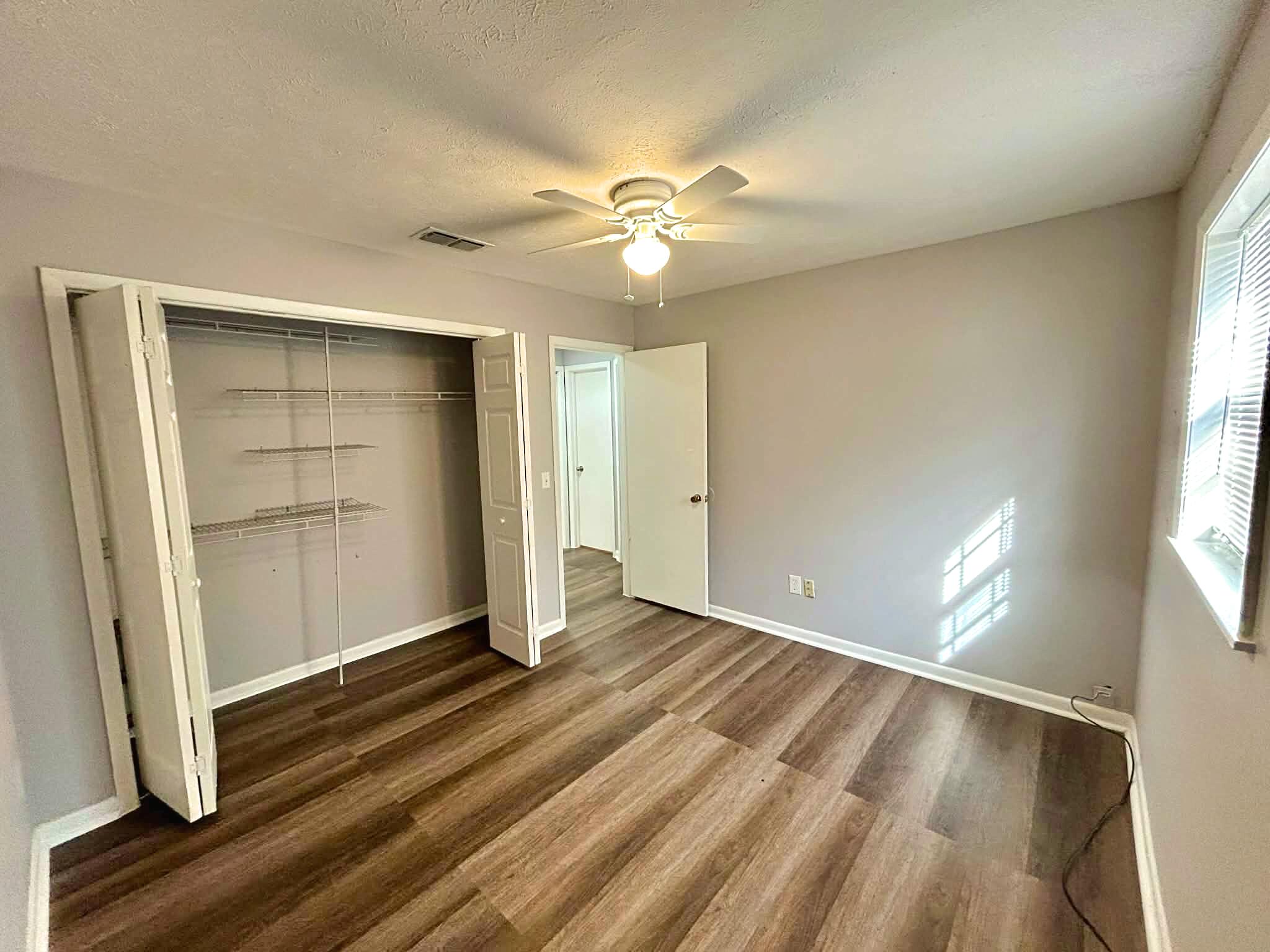 341 Central Avenue, Unit 1 Clewiston, FL 33440 - Photo 5 of 11 wooden floor in an empty room with a window
