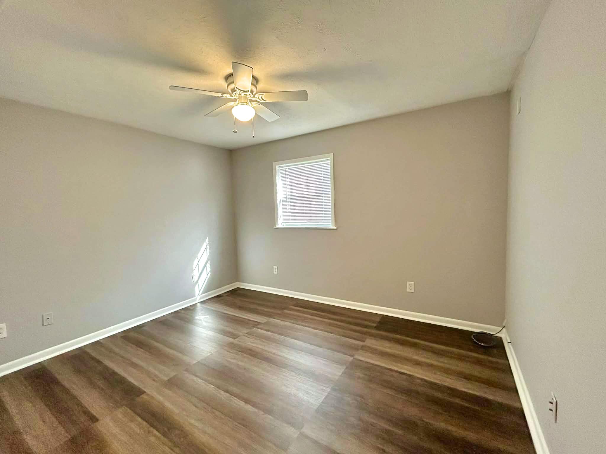 341 Central Avenue, Unit 1 Clewiston, FL 33440 - Photo 6 of 11 an empty room with wooden floor fan and windows