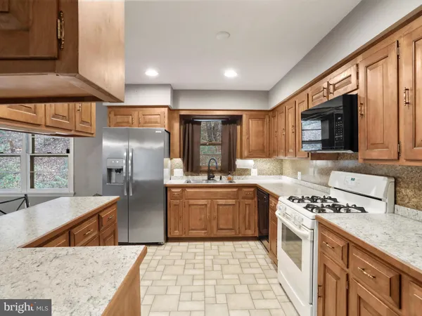 a kitchen with stainless steel appliances granite countertop a refrigerator a stove top oven a sink and dishwasher