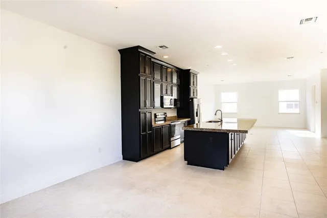 a kitchen with stainless steel appliances kitchen island granite countertop a refrigerator and a stove