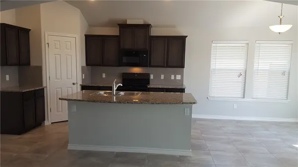 a kitchen with stainless steel appliances granite countertop a sink a stove and a refrigerator with wooden cabinets