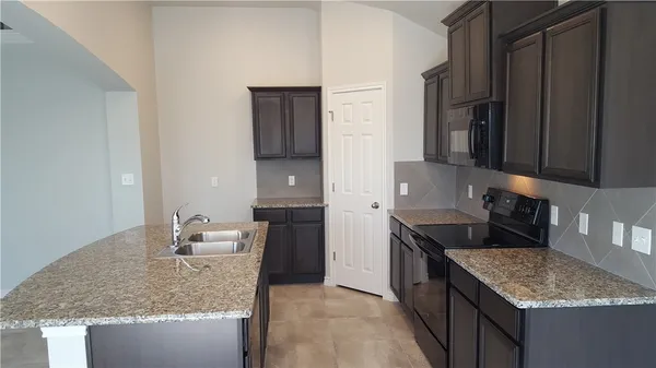 a kitchen with granite countertop a sink and a stove
