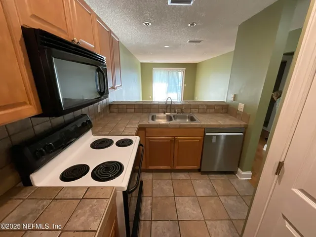 a view of a kitchen with a sink and a refrigerator