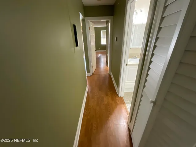 a view of a hallway with wooden floor and a door