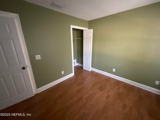 a view of a hallway with wooden floor and a door