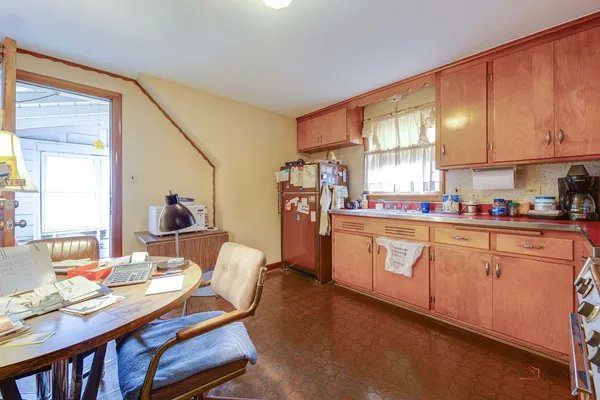a open kitchen with stainless steel appliances granite countertop a refrigerator a sink dishwasher a dining table and chairs with wooden floor
