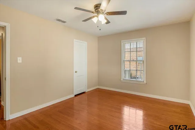 a view of empty room with wooden floor and fan