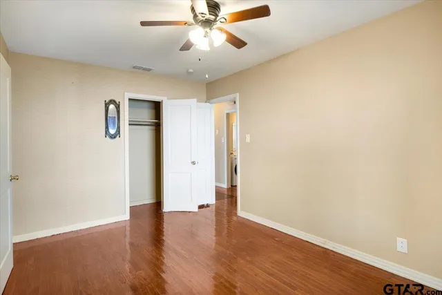 an empty room with wooden floor chandelier fan and closet area
