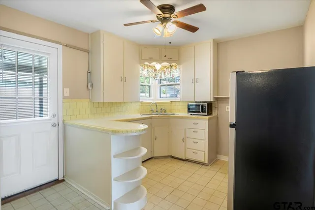 a kitchen with white cabinets and refrigerator