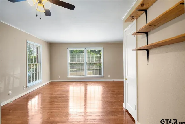 a view of an empty room with wooden floor and a window