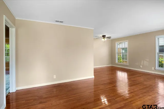 a view of an empty room with wooden floor and a window