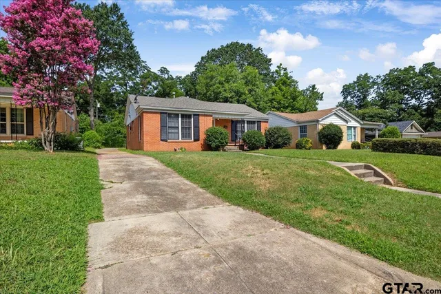 a front view of a house with a yard and trees