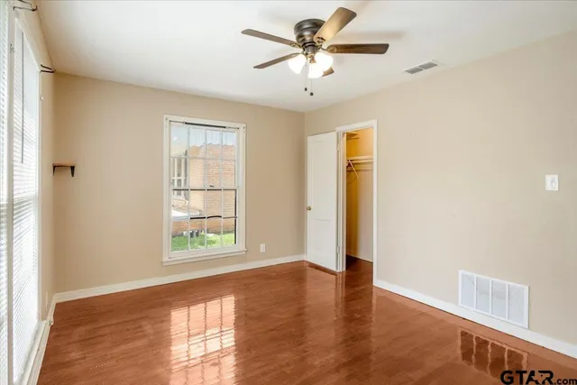 a view of an empty room with a window and wooden floor