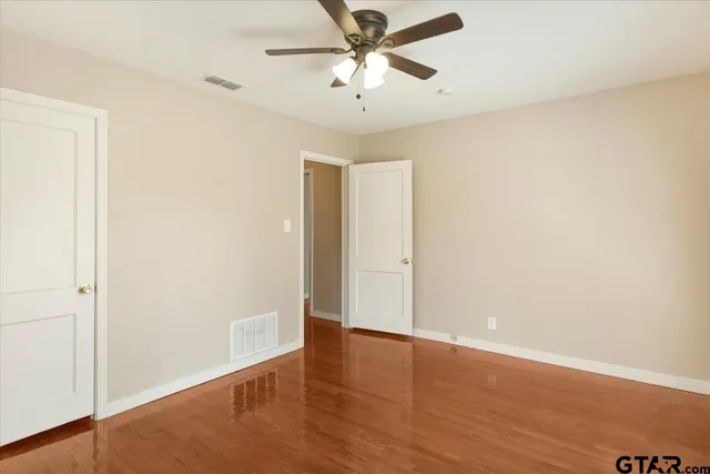 a view of a room with wooden floor and a ceiling fan