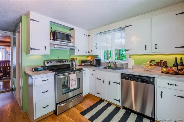 a kitchen with stainless steel appliances a stove a sink cabinets and a window