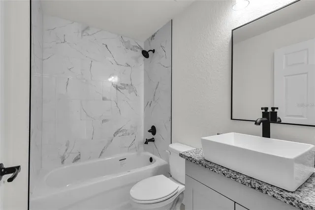 a bathroom with a bathtub shower sink vanity mirror and toilet