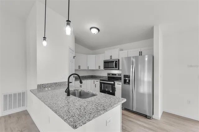 a kitchen with stainless steel appliances granite countertop a sink refrigerator and microwave