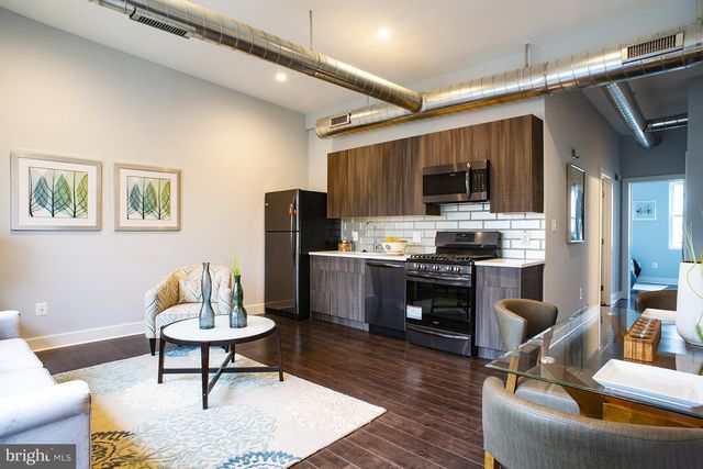 a living room with stainless steel appliances furniture and a kitchen view