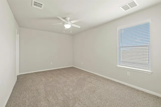 an empty room with a window and ceiling fan