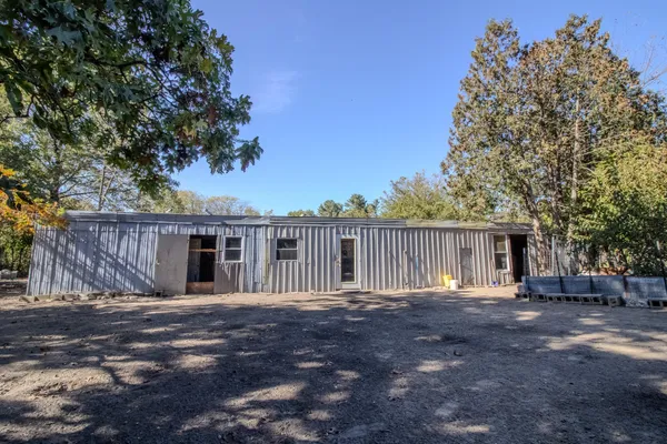 a backyard of a house with large trees and wooden fence
