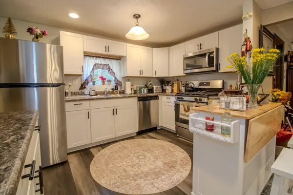 a kitchen with a refrigerator a stove a microwave a sink and dishwasher with wooden floor