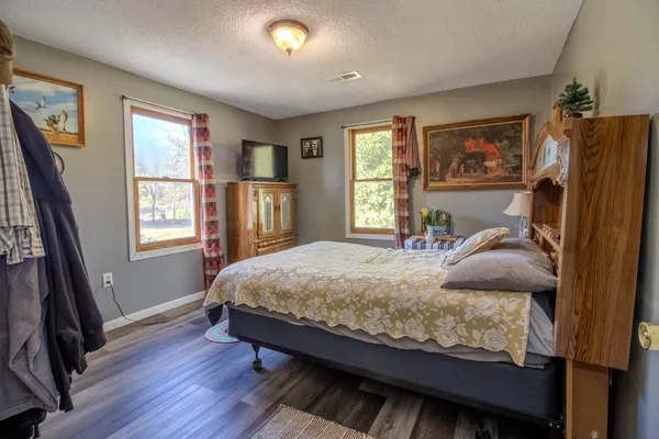 a bedroom with a bed wooden floor and window