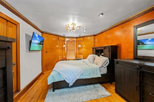 a bedroom with a bed dresser and a large window