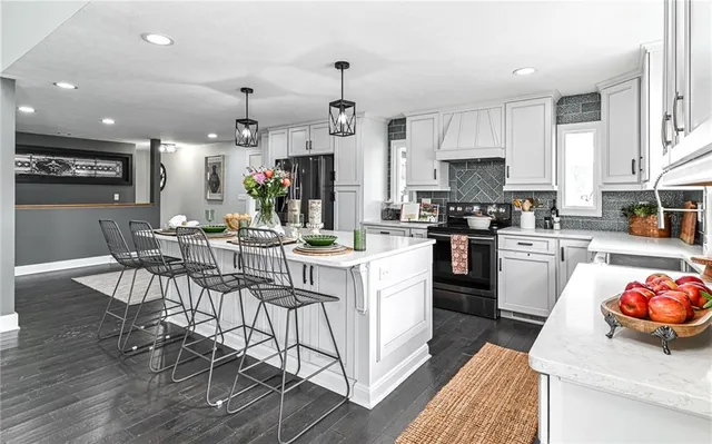 a kitchen with stainless steel appliances kitchen island granite countertop a refrigerator and a stove top oven