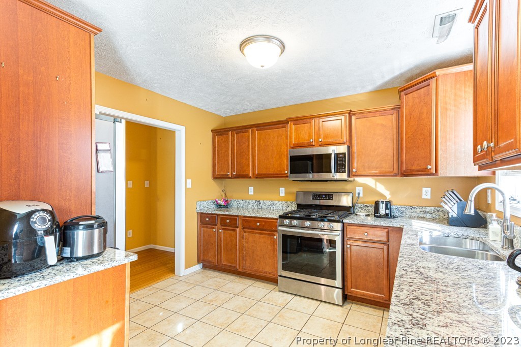 117 Ridgeview Drive Raeford, NC 28376 - Photo 11 of 31 a kitchen with stainless steel appliances granite countertop a stove top oven a sink dishwasher a dining table and chairs with wooden floor