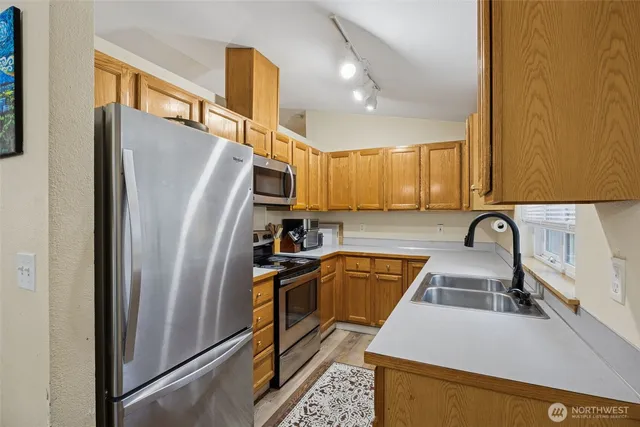 a kitchen with stainless steel appliances granite countertop a refrigerator a stove and a sink with wooden floor