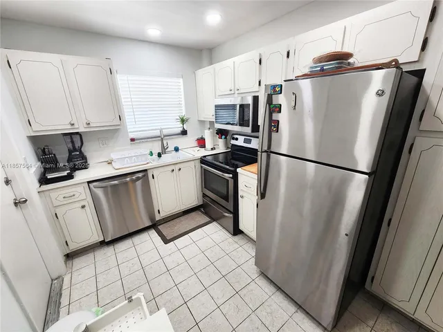 a kitchen with white cabinets stainless steel appliances and a refrigerator