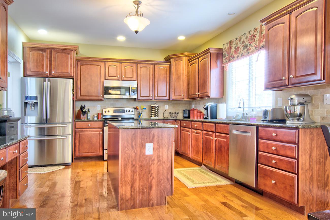 816 Shadebrush Ridge Road West Chester, PA 19382 - Photo 16 of 44 a kitchen with stainless steel appliances granite countertop a refrigerator a sink dishwasher a stove and a dining table with wooden floor