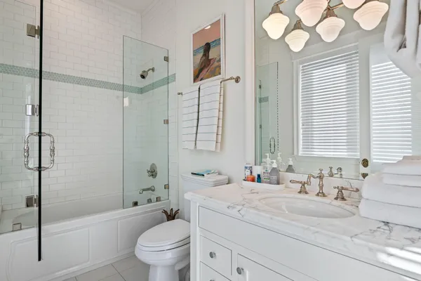 a bathroom with a granite countertop sink a toilet a large mirror and shower