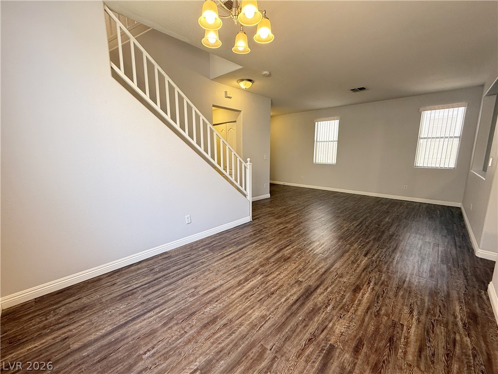 2185 Polynesia Circle Henderson, NV 89074 - Photo 6 of 37 A spacious living area features rich wood-look flooring and a prominent staircase leading to the upper level.