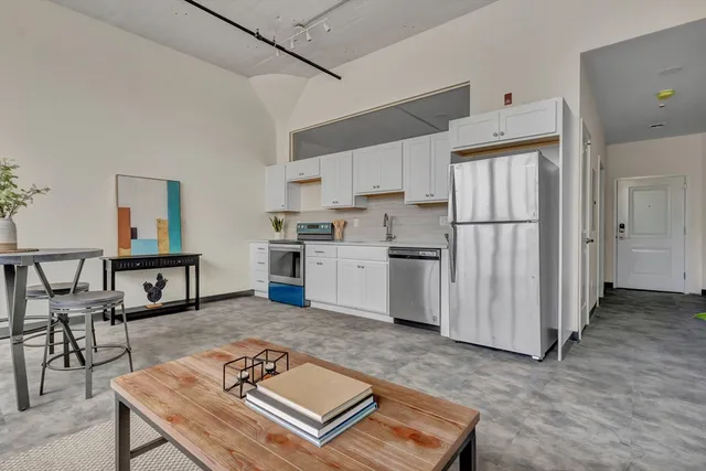 a living room with stainless steel appliances furniture stove and kitchen view