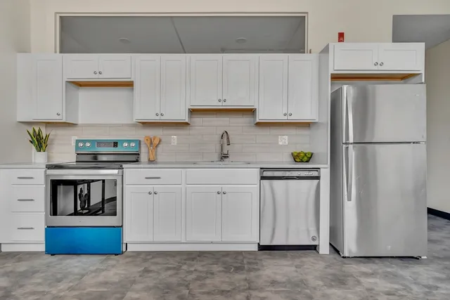 a kitchen with stainless steel appliances granite countertop a refrigerator sink stove and white cabinets