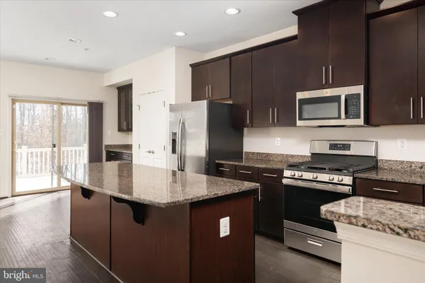 a kitchen with granite countertop stainless steel appliances a refrigerator a stove a sink cabinets and a refrigerator