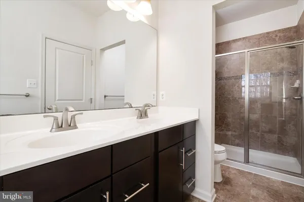 a bathroom with a shower sink vanity mirror and toilet